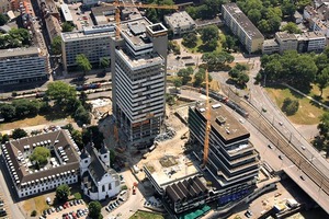  Einer der markantesten Eingriffe in das ehemalige Lufthansa-Haus war die Niederlegung von drei Ebenen einer Parkgarage mit einer spiralförmigen Auffahrt. Durch den Rückbau der Park­ebenen schälten die Architekten zwei Hochpunkte mit sieben und neunzehn Bürogeschossen aus der terrassierten Bauform heraus, zwischen denen der öffentlich begehbare Kennedyplatz entstand 