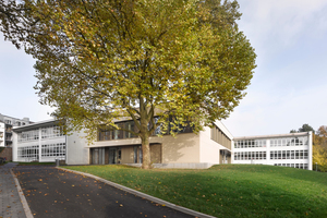  Der Neubau legt sich als Riegel zwischen die beiden „Türme“ des Altbaus. Das ermöglicht größzügige Grünflächen und den Erhalt vieler alter Bäume auf dem Schulhof 