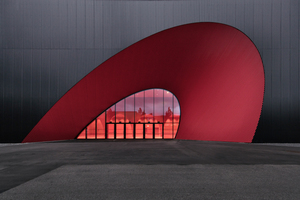  Besucher betreten die imposanten Neubauten über die markant elliptisch geformten, leuchtend roten Halleneingänge.  