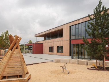 Das zweistöckige Gebäude, das einschließlich der Geschosstrenndecken aus Holz besteht, wurde auf eine teils im Erdreich liegende Tischtennishalle aufgesetzt. 