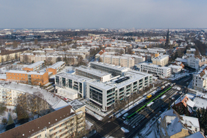  Das Luftbild zeigt, wie der gesamte Gebäudekomplex die „Neue Mitte“ im Stadtteil Herrenhausen bildet. Im Vordergrund ist die Stadtbahnhaltestelle zu sehen 