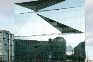  In der gefalteten äußeren Glashülle spiegeln sich Himmel und Betonfassaden 