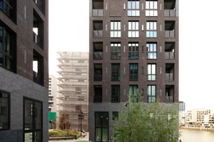  Blick westlich über den kleinen Hof auf den Turm des Duos: Hier ist die zunehmende Öffnung der Mauerwerksfassade über dem Sockel sehr schön abzulesen. Während in Straßennähe die Fenster-und Loggienöffnungen eher schmal ausfallen, weiten sie sich nach oben hin zusehends auf. Blindfenster im Raster dort, wo Fenster innen nicht möglich sind. Die schmalen Lüftungsfenster sind – wenn blind gemauert – mit Steinen aus dem Sockel gefüllt 