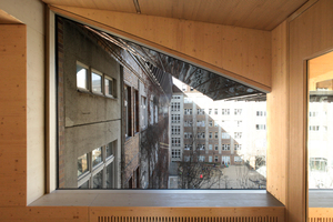  Die Übergänge von Bestand zum Aufbau sind fließend, hier ein Hofblick unterhalb der Aula. Sämtliche Heizkörper sind so eingepackt, dass man auf ihnen sitzen kann. Die geschlitzte Holzdecke dient der akustischen Regulierung 