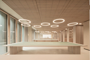  Über den Lesetischen schweben filigrane LED-Ringpendelleuchten in zwei Größen, angeordnet in Gruppen, die sich auf die Tischzonen darunter<br />beziehen. Die Pendelleuchten bestehen aus einem zarten Direktlichtprofil mit einer massiven Diffusorabdeckung 