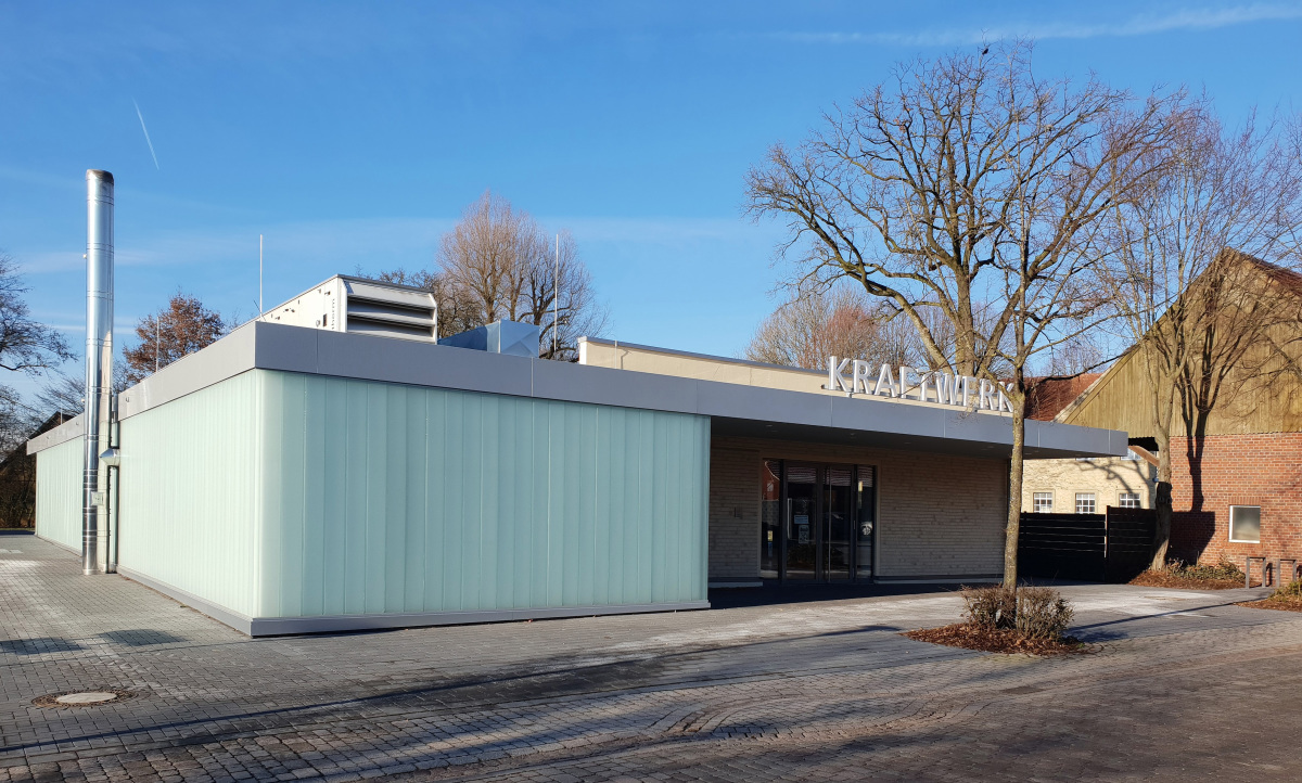 Der Neubau, ein Funktionsriegel der u.a. die Heizung mit Hackschnitzellager und Wärmespeicher aufnimmt, erhielt eine vollflächige Haut aus Industrieglas, die in verschiedenen Farben beleuchtet werden kann. 