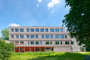  Der rote Unterschnitt im Erdgeschoss des Neubaus markiert den Eingangsbereich und zudem die Verbindung zum Altbau, wobei sich die Farbwahl auch auf dem Dachgeschoss wiederfindet 