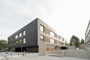  Der kompakte Schulbau setzt auf Kontraste zwischen hell und dunkel und das sowohl von außen als auch von innen. Prägende Materialien sind Holz und Beton und das in präziser Fügung 