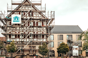  Vorne der Altbau in der Sanierung, im Hintergrund der quer angedockte Neubau samt keramischer Fassade 
