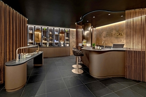 Bronzefarbene Möbel, Lampen und Metallvorhänge verbreiten im AWAY-Spa-Wellnessbereich einen Hauch von Luxus, der durch anthrazitfarbene Keramikfliesen sowie bronzefarben schimmernde Spachtelputze ergänzt wird