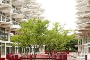  Der rote Innenhof dient als Treffpunkt für die Bewohnerinnen und überspannt die darunterliegende Garage. Die runden Öffnungen erlauben den Blick ins Sockelgeschoss und lockern die Struktur auf 