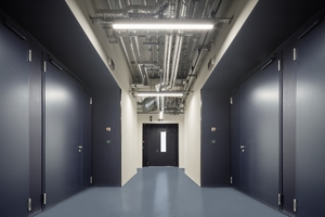  Das dunkle Blau der Fassade setzt sich auch im Innenraum des IOF fort, wobei in den hinter den Türen verborgenen Forschungsbereichen oft nur ein Quantenlaser für das richtige Licht sorgt 