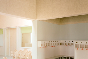  Warme Holzatmosphäre: Im Innenraum - hier der Spielflur - prägen unverkleidete Schallschutzelemente das Erscheinungsbild  