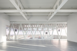  Das Obergeschoss ist durch transparenten Materialien charakterisiert wie Glas und Polycarbonat. Vom kleinen Aufwärm-Sportraum blickt man bereits von oben in die Halle 