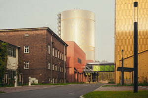  Links Teile der Bestandsbauten des Heizkraftwerks Süd, in zweiter Reihe die Gasanlage und rechts der gelbe Kraftwerksneubau, im Hintergrund in metallischer Zurückhaltung der Wärmespeicher 