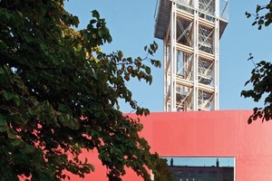  Foto 7: Ein 2-geschossiger Holzbau mit einer Signalfarbe bedacht stellt das Ausstellungsgebäude. Es steht auf einem leicht erhöhten Sockel. Man betritt das Foyer und das Café über eine Rampe  