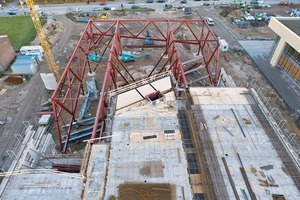  Um das Stahlfachwerk mit seiner weiten Auskragung, dem Eigengewicht und den Ausbauten in der Waage zu halten, wird die Fassadenachse über eine vorgespannte Hochhängekonstruktion aus Stahlzuggliedern stabilisiert. Auf der Dachfläche wurden verstärkte und hoch bewehrte Deckenstreifen vorgesehen, über die die Horizontallasten zurückgehängt und in die aus­-steifenden Wände geleitet werden können 