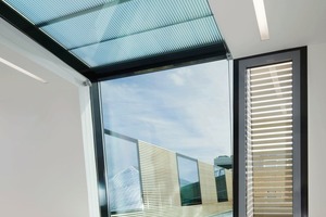  Außenbündig und Über-kopf folgen die Fenster den Dachneigungen. Ein lichtlenkendes Isolierglas mit Sonnenschutzbeschich­tung Arcon Sunbelt Silber 39/25 und Zwischenraumfolie erreichen einen U-Wert von 6,0 W/m²K. Bei direktem Sonneneinfall bekommt die Überkopfverglasung elegante Markisen, die geräuschlos unten und oben zugefahren werden können 