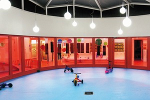  8) Ein ringförmiger Innenraum, wie ein überdachter Hof im Inneren des Gebäudes bildet das Zentrum des 1.350 m² großen Kindergartens. Von hier aus öffnen sich strahlenförmig 6 Aufenthaltszonen, die alle ihren räumlichen Abschluss durch geschosshohe Glasfronten haben 