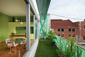  Im Obergeschoss verläuft ein Deck, das mit grünem Kunstrasen belegt ist und von der bedruckten Fiberglasfassade nach außen abgeschirmt wird 