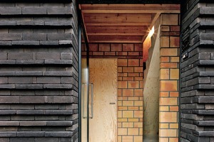  Die Fassade mit den versetzten Back­-steinen entstand gewissermaßen durch Zufall auf der Baustelle: Ge-plant war eine glatte, durchlaufende Backsteinfassade, bei der die Über-stände der unterschiedlich großen Ziegel auf der Seite der Wärmedämmung liegen sollte. Bei Testversuchen entschloss man sich jedoch aus ästhetischen Gründen, die Schichtung umzudrehen und die Steine auf der isolierten Seite bündig zu legen 
