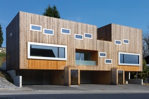  Foto1: Das Wohnhaus aus Holz ist 22m lang. Hier haben drei Familien ihr zuhause gefunden. Zwei große Panoramafenster zeigen die Wohnräume der größeren Familien an während die Wohnung der Tante in der Mitte platziert wurde. Nach außen erkennt man diese Wohnungseinheit an der tiefliegenden Loggia 