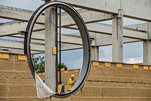  Die Stampflehm-Elemente sind vor das Stahlbeton-Tragwerk gesetzt. Übereinander geschichtet, durch­brechen vier runde Fenster auf jeder Seite die Fassaden 