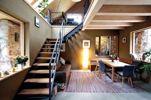  Wohn-/Essraum: Die Treppe führt zum Arbeits- und Wohnzimmer im Dachgeschoss. Der Lehmputz bleibt sichtbar, ebenso die Holzträger der Decke über dem gestrichenen Heiz­estrich. Der Luftraum dient auch der natürlichen Belichtung 