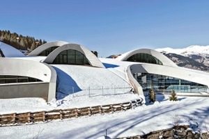  Die in die Topografie des Ortes eingebundene Dachskulptur lässt sich geometrisch wie ein winziger Ausschnitt aus der Oberfläche eines Schwimmringes begreifen. Im Winter erscheint das Gebäude durch sein Dach wie eine seichte Erhebung der Schneelandschaft 