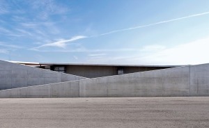  Die vor der Halle platzierten halboffenen und geschlossenen, aus Ortbeton gegossene Lagerplätze der Anlage fassen und strukturieren den Vorplatz 