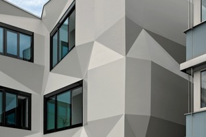  In den fensterlosen Bereichen entwicklt die Fassade ihre Origamiqualität. Licht und Schatten geben ihr eine gefaltete papierne Wirkung 