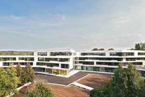  Der Pausenhof orientiert sich in den Nordwesten. Im Rücken der Schule liegt eine vielbefahrene Straße. Dies veranlasste die Architekten, eine Lärmschutzmauer um die Schule zu ziehen  