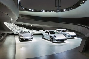  Bis auf die hell erleuchtete Ebene mit dem Schwarm aus Porsche-Modellen ist das Pavilloninnere dunkel und schwarz gehalten 