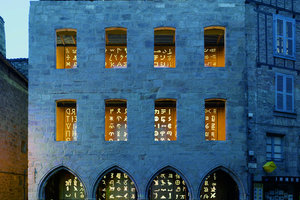  In der Nacht leuchtet die neue mit Schriftzeichen durchbrochene Fassade wie eine Laterna Magica.Die Fassade des Neubaus liegt einen Meter hinter der des Altbaus 