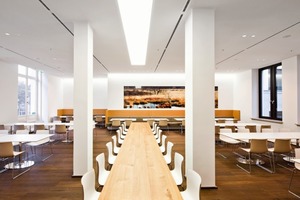  Etwas mehr Spielraum hatten die Architekten für die Gestaltung der Cafeteria, der Konferenzzonen oder der sich im Altbau befindlichen Kantine. Die entworfenen Möbel in der Cafeteria und in der Kantine offenbaren einen Blick fürs Detail: Kaffeemaschinen, Getränke-, Brötchen und Tablettausgabe sind in einemrechteckigen, orange bedrucktem Glas verkleideten Möbel untergebracht ,das nicht nur flächenbündig, sondern auch praktisch ist. Und die geschwungen-versetzten Ledermöbel bieten überraschend neue Gesprächsmöglichkeiten 