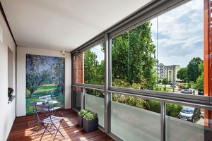  Das ungedämmte Balkonsystem SL Modular von SOLARLUX bietet einen guten Wetter- und Schallschutz. Im geschlossenen Zustand erreicht es eine Schallreduktion von 21 dB. Die perforierten roten Schiebeelemente dienen dem Sicht- und Sonnenschutz und prägen gleichzeitig die Fassade 