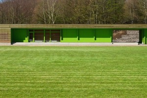  Leuchtendes Grün hinter Holzlamellen für Clubraum und Umkleiden  – das Sportlergebäude in Hemer  